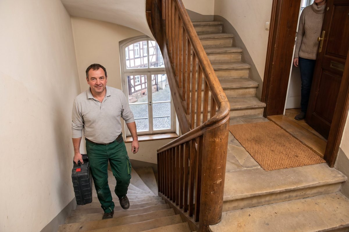 Sanitär-Fachkraft im Treppenhaus eines Altbaus – Beispielbild für Fulda